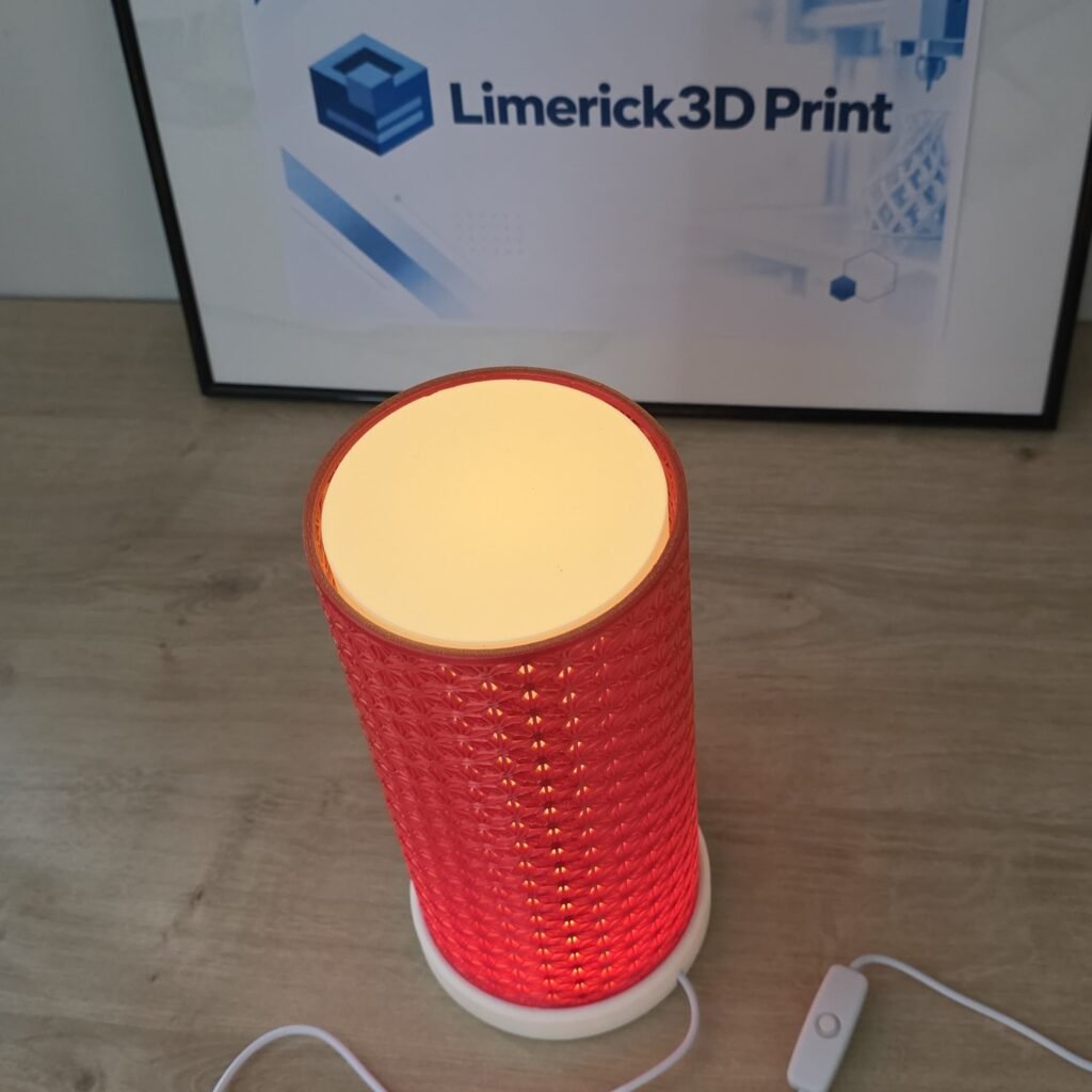 Kumiko Japanese LED table lamp switched on, with a red 3D printed lattice shade glowing warmly