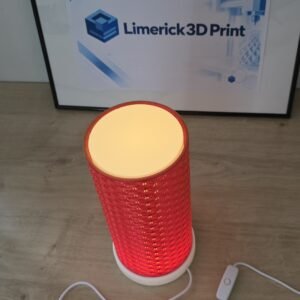 Kumiko Japanese LED table lamp switched on, with a red 3D printed lattice shade glowing warmly